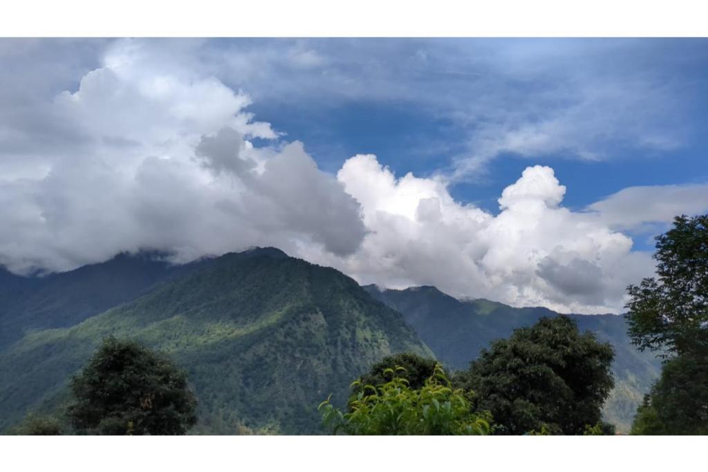 a view of a mountain with clouds in the sky at Prince Homestay & Restaurant in Rudraprayāg