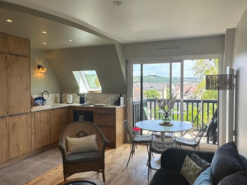 a kitchen and living room with a table and a balcony at Appartement Duplex 2 Pièces Centre-Ville avec Balcon et Internet Inclus - FR-1-487-383 in Cabourg