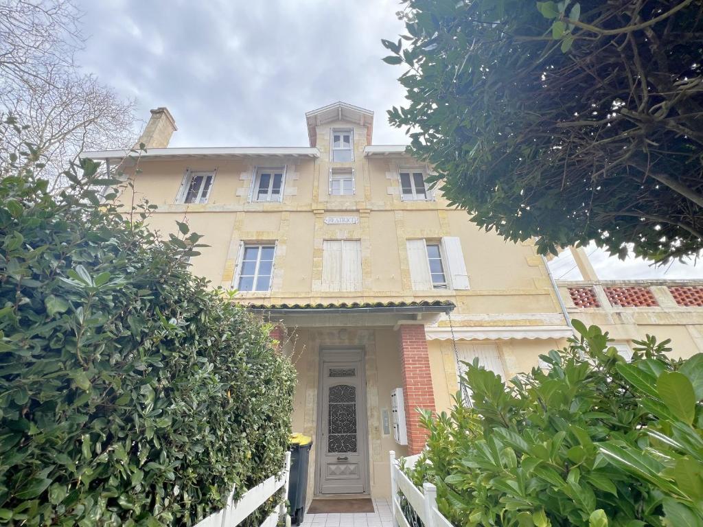 une grande maison jaune avec une porte devant elle dans l'établissement Bel Appartement T2 Près de la Plage - Idéal pour 4 Personnes - FR-1-474-272, à Arcachon