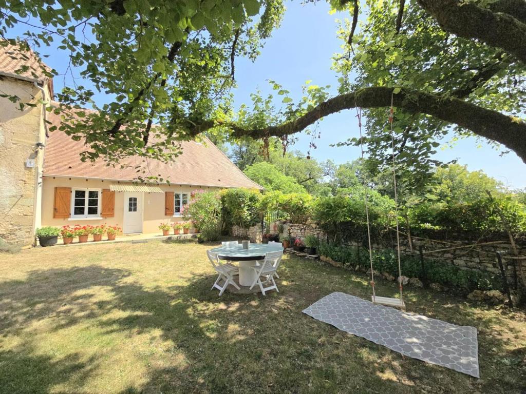 un patio con una mesa y un columpio en Gîte de charme avec cheminée en Dordogne - FR-1-616-466, en Tourtoirac
