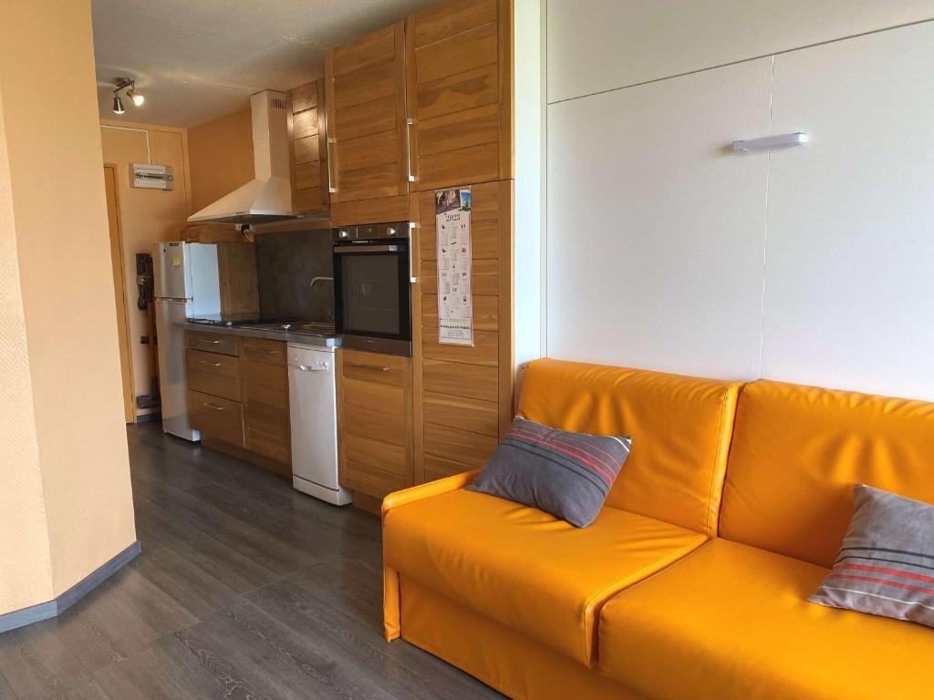 a living room with an orange couch and a kitchen at Studio rénové avec loggia et parking privatif - FR-1-553-306 in Balaruc-les-Bains