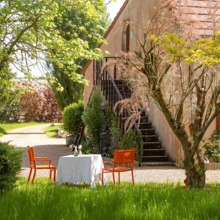 une table et des chaises assises dans l'herbe devant un bâtiment dans l'établissement Gîte Le Nid aux Papillons, à Palinges