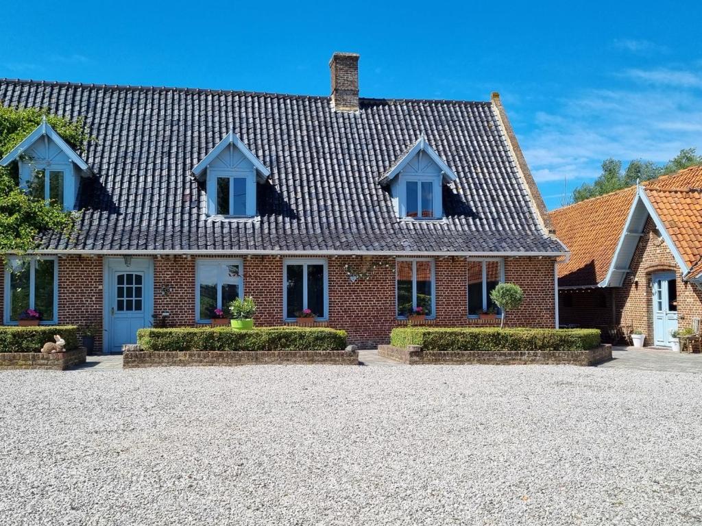 una casa di mattoni con tetto su un vialetto di ghiaia di Gîte familial 15 pers avec jardin, spa et activités près de Cassel - FR-1-510-233 a Oudezeele