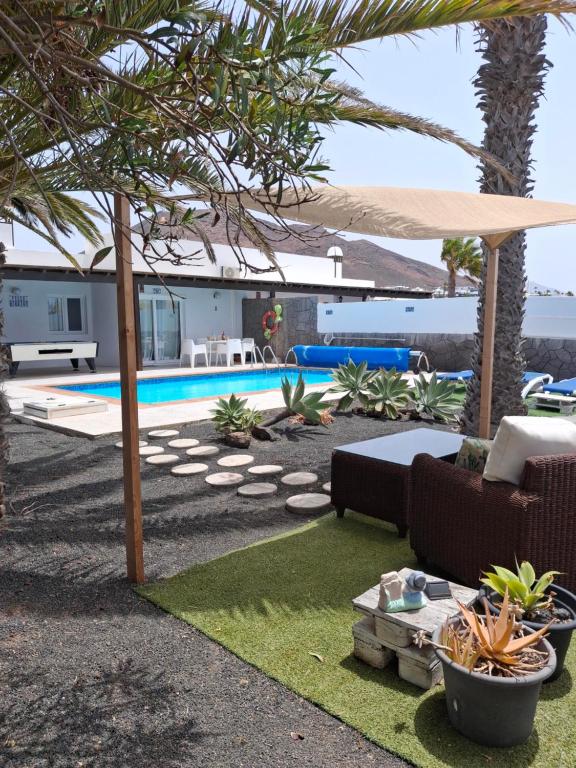 einen Hinterhof mit Pool mit Sofa und Sonnenschirm in der Unterkunft Villa Mariola in Playa Blanca