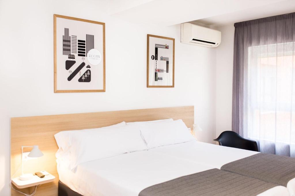 a white bedroom with a bed and a window at Rooms Ciencias in Valencia