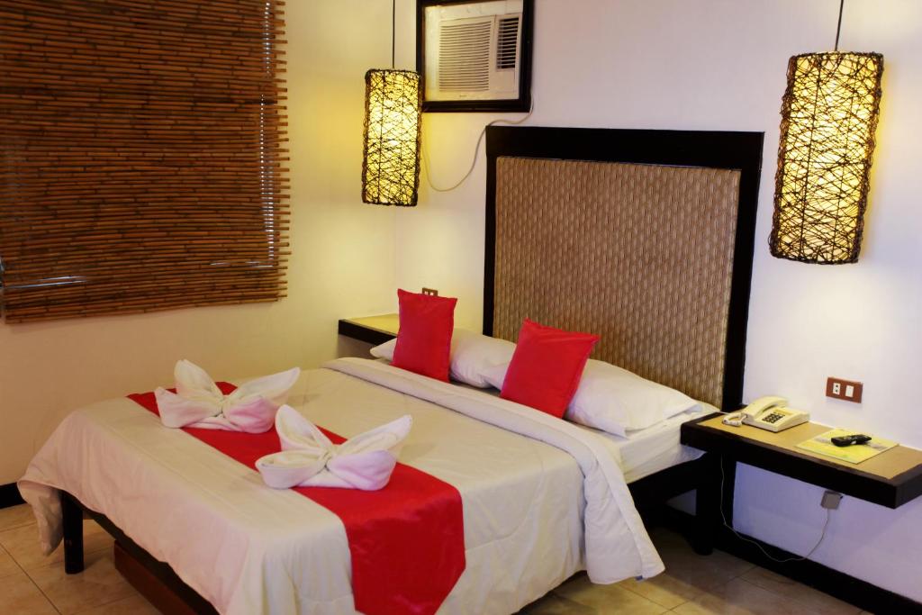 a bedroom with two beds with red and white pillows at Eagle Point Beach and Dive Resort in Mabini