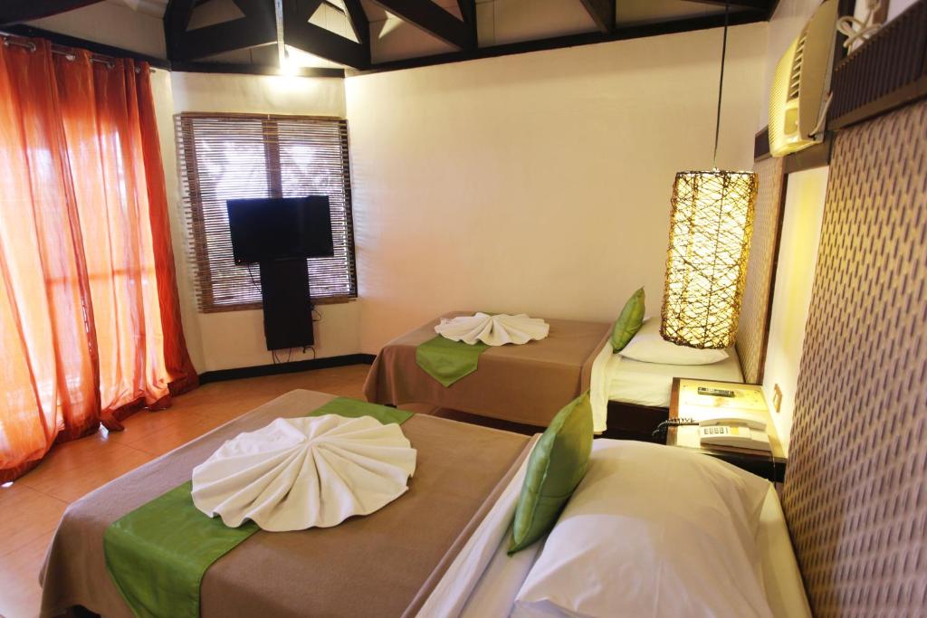 a room with two beds and a flat screen tv at Eagle Point Beach and Dive Resort in Mabini