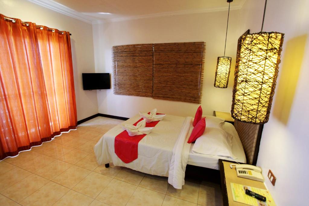 a bedroom with a bed with red and white sheets at Eagle Point Beach and Dive Resort in Mabini