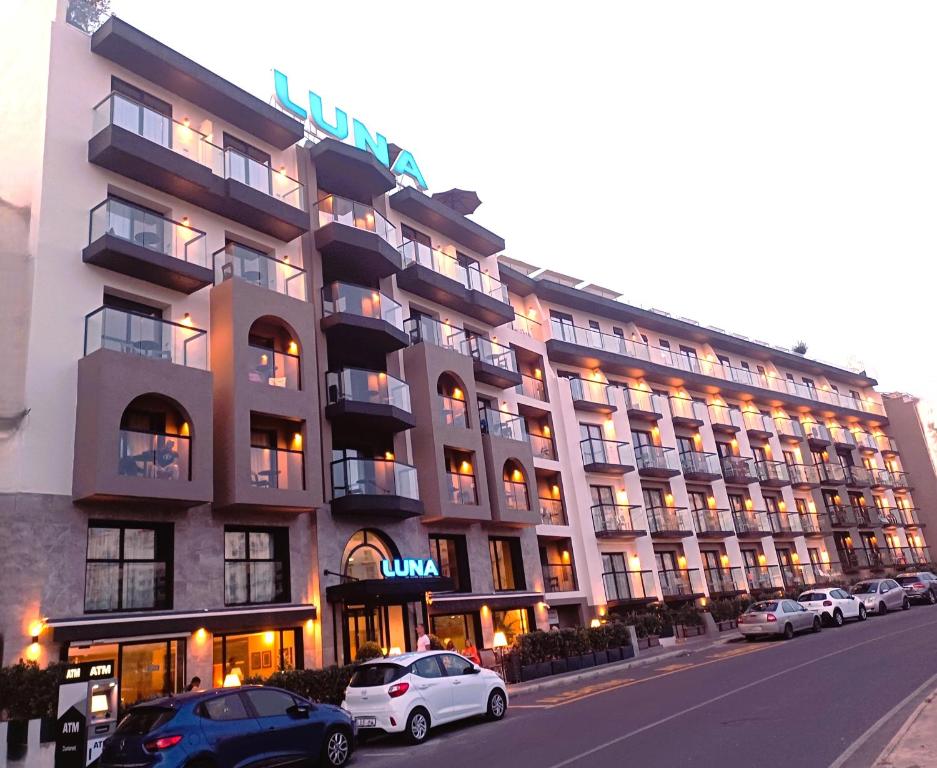 a large building with cars parked in front of it at Luna Holiday Complex in Mellieħa