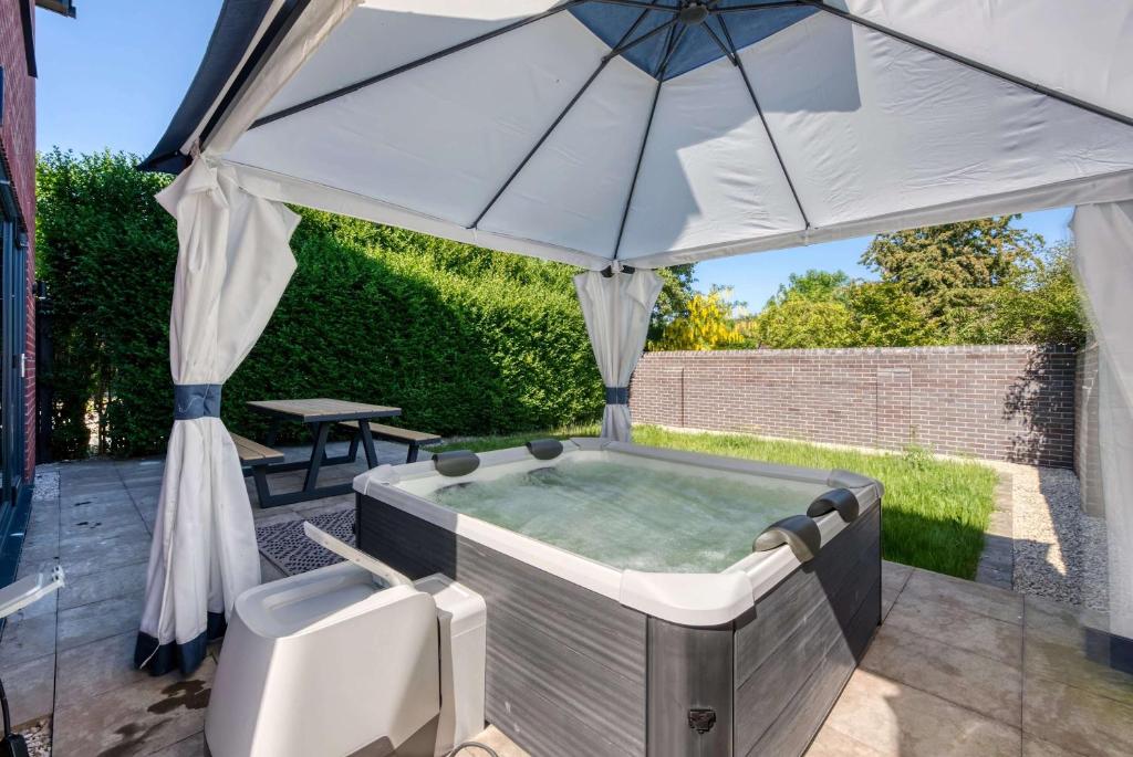 a hot tub with an umbrella on a patio at Modern 3BR Home in 24 Breeden Dr Near M6, NEC & Airport Hot Tub, Netflix, Free Parking in Curdworth
