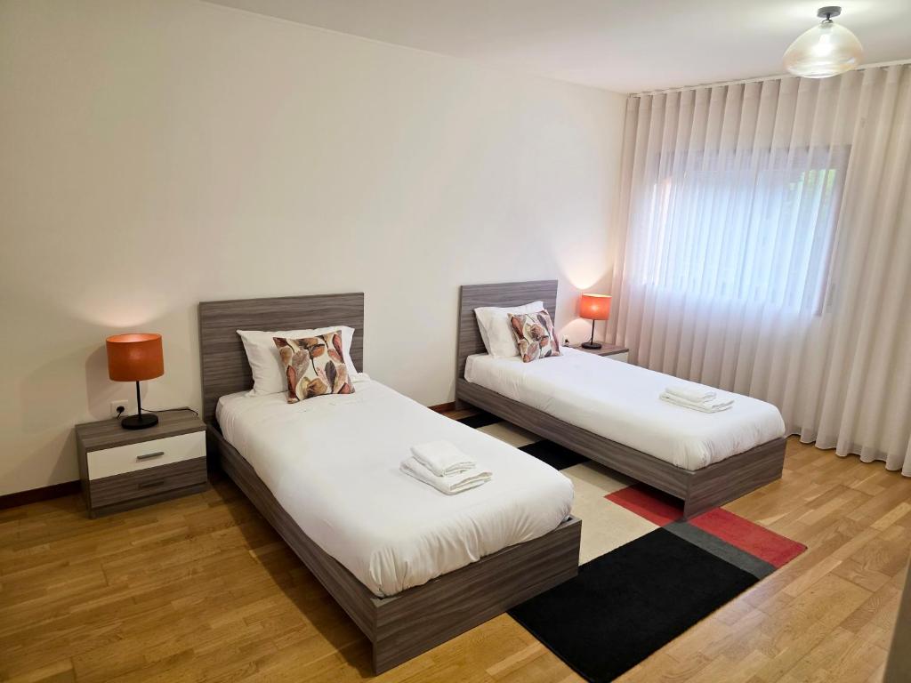 Un dormitorio con dos camas y una ventana. en Villarmo cais, en Viana do Castelo