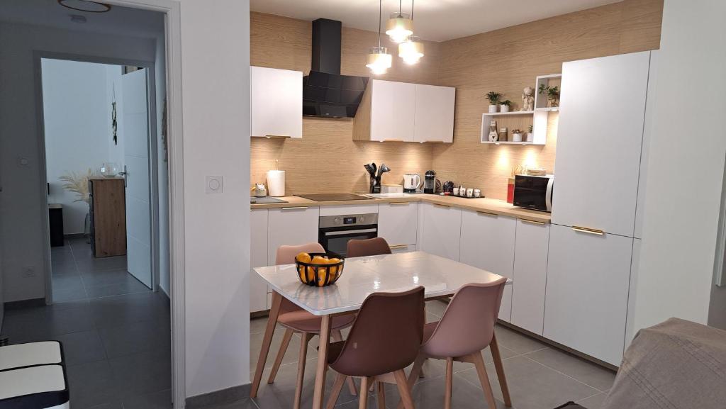 a kitchen with a table and chairs in a kitchen at LE SNOOKYBAY - Appartement Neuf - Classé 3 étoiles in Cavalaire-sur-Mer
