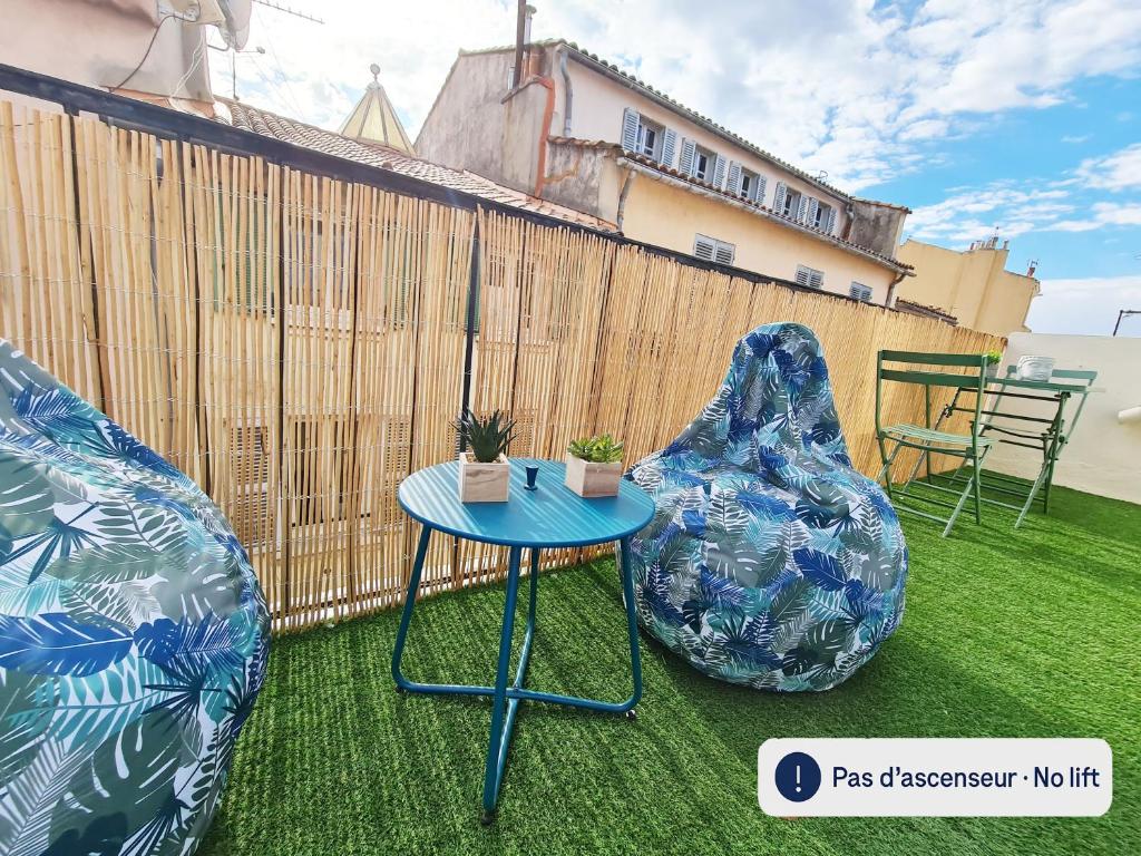 d'une terrasse avec 2 chaises et une table sur gazon. dans l'établissement GregBnb - Centre Ancien - Studio Roof-Top - CLIMATISÉ - 5eme étage, à Toulon