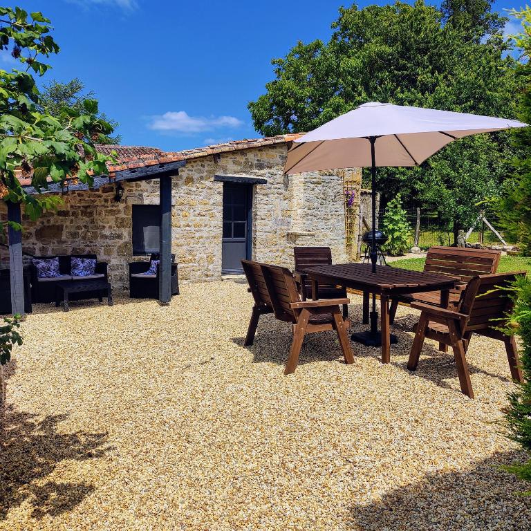 a patio with a table and chairs and an umbrella at Les Écuries in Empuré