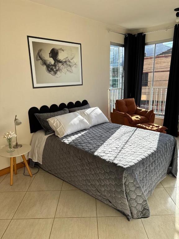 a bedroom with a large bed and a chair at APARTAMENTO no CENTRO 1 WI-FI GARAGEM in Vacaria