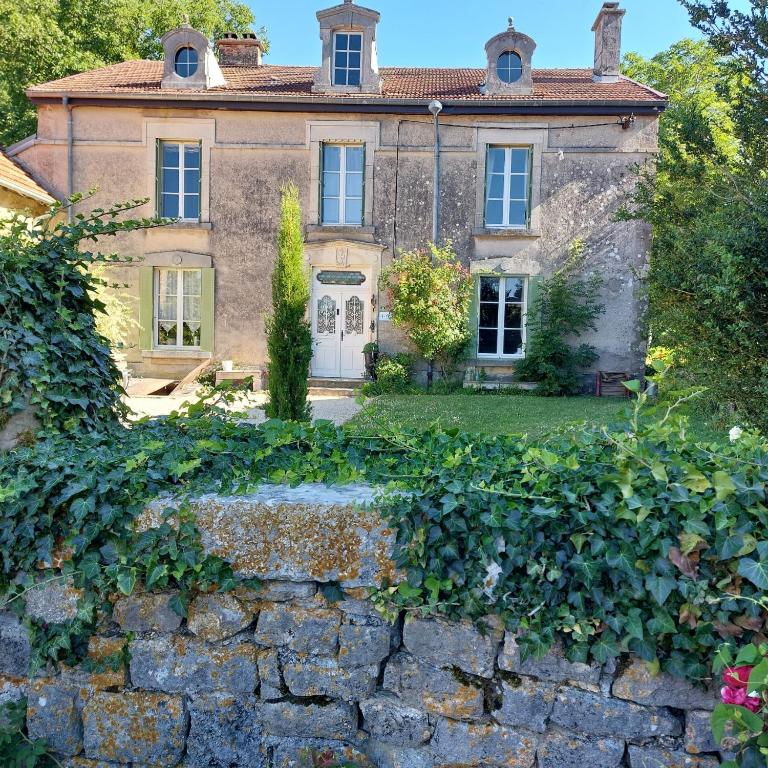 une maison ancienne avec un mur en pierre devant elle dans l'établissement Le Pasteur Danseur, à Graffigny-Chemin