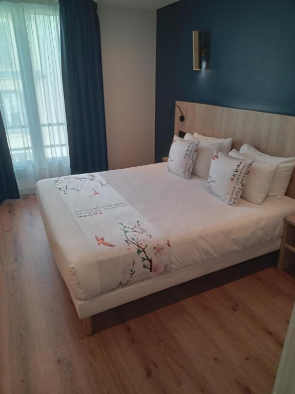 a bedroom with a bed with white sheets and pillows at Hotel Modern Est in Paris