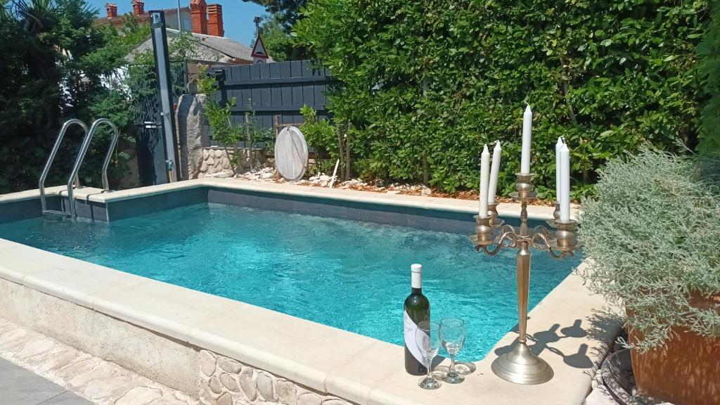 a swimming pool with a candle and a bottle of wine at Villa Lido 145 m2 with pool in Krnica