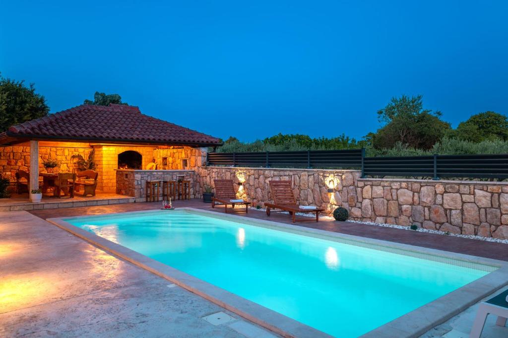 a swimming pool in a backyard with a stone wall at Villa Silente in Oklaj