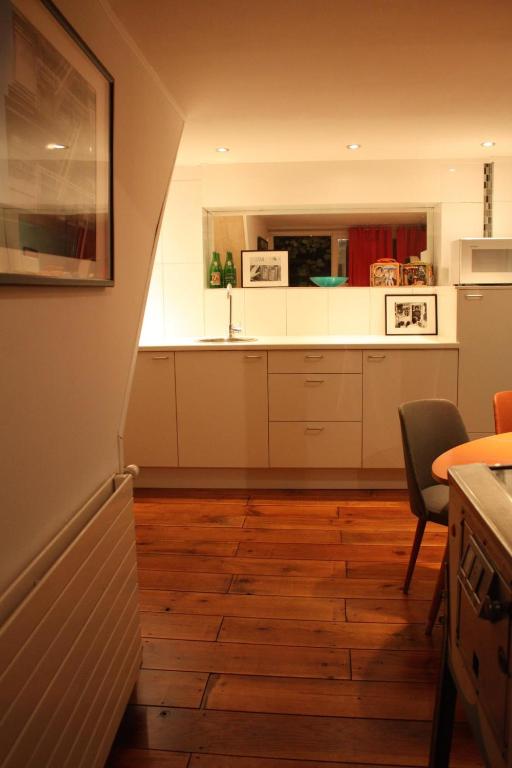 una cucina con armadietti bianchi e pavimenti in legno di De Buitenmuur - Vintage Suite & Bohemian Loft, elk met Privé-ingang en Jacuzzi a Turnhout