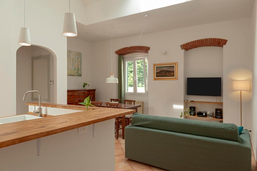 Una cocina y una sala de estar con un sofá verde. en ELEGANTE APPARTAMENTO A POCHI PASSI DAL MARE E DAL CENTRo, en Livorno