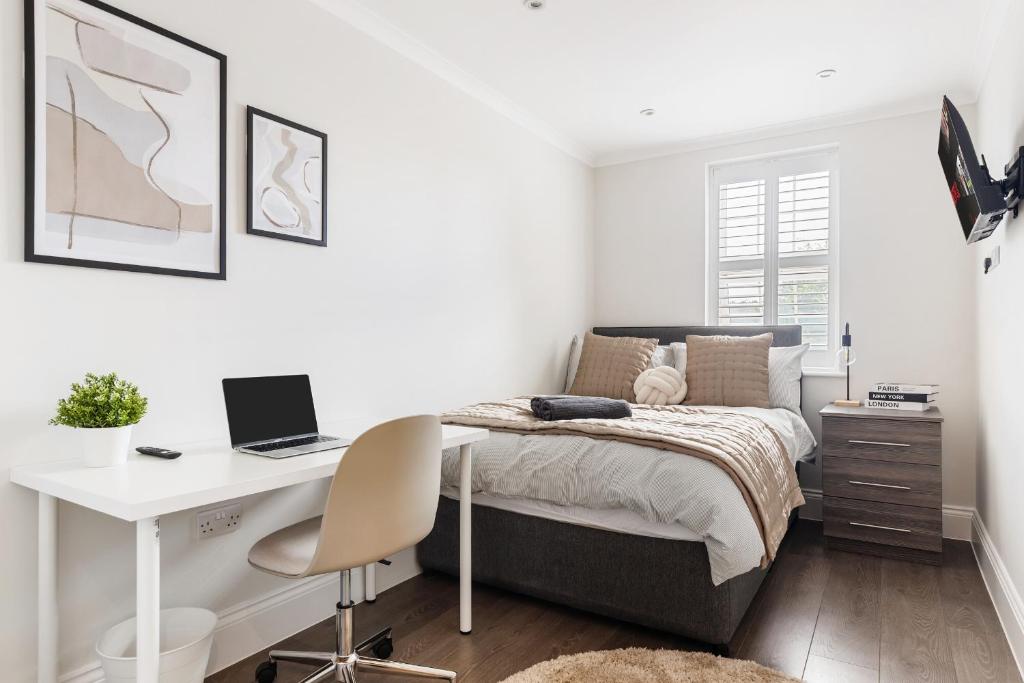 a bedroom with a bed and a desk with a laptop at Mallside Meadows - Hot Tub, Games Room, Garden in New Southgate