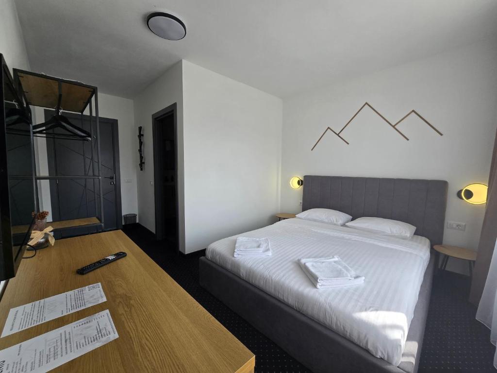 a hotel room with a bed and a wooden table at Nort Inn - Luncile Prigoanei, Sureanu, Oasa, Transalpina in Tău Bistra