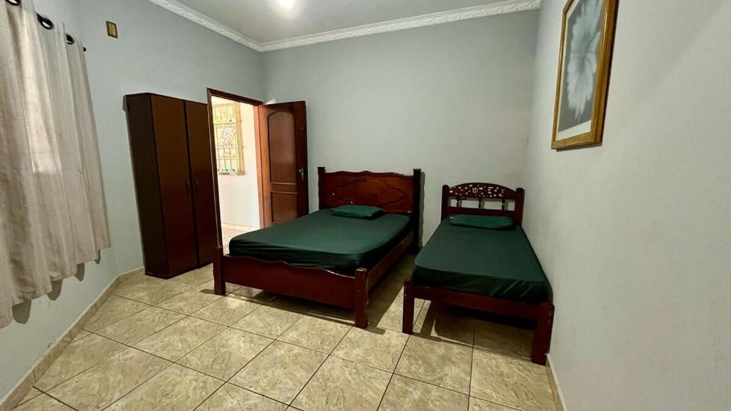 ein Schlafzimmer mit zwei Einzelbetten und einem Fenster in der Unterkunft Área de Lazer Sertãozinho in Sertãozinho