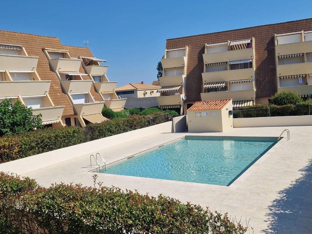 une piscine devant un immeuble dans l'établissement Studio cabine avec piscine, plage directe, terrasse et parking - Animaux acceptés - FR-1-387-53, à Marseillan