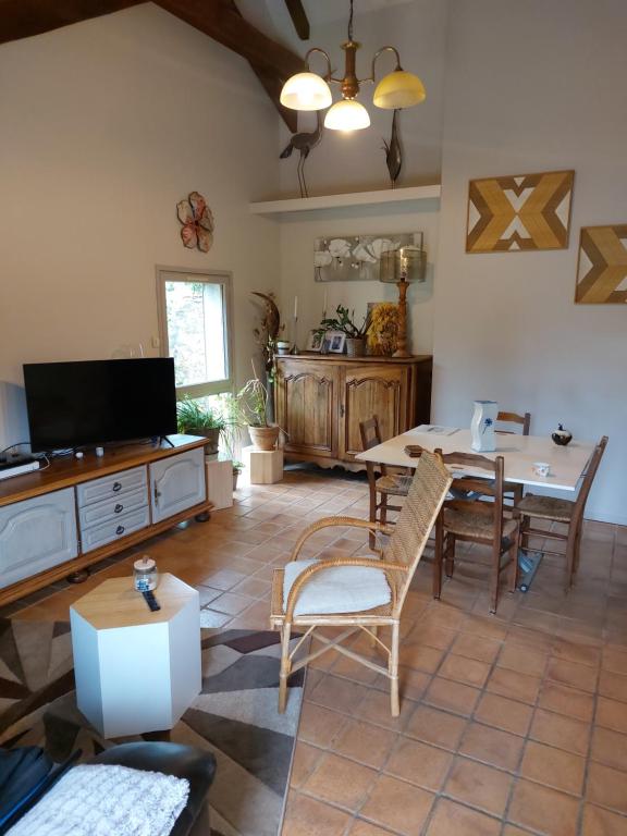 un soggiorno con TV, tavolo e sedie di Maison à la campagne a Beyssac