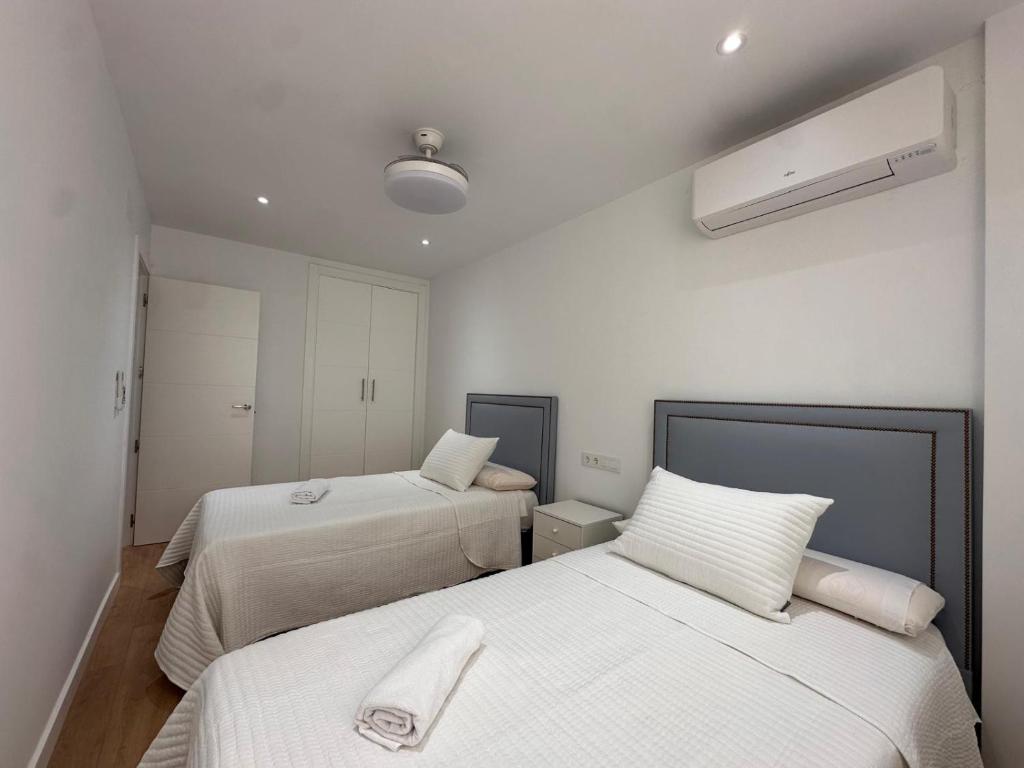 a bedroom with two beds with white sheets at A&N Seafront 2 Torre del Mar in Torre del Mar