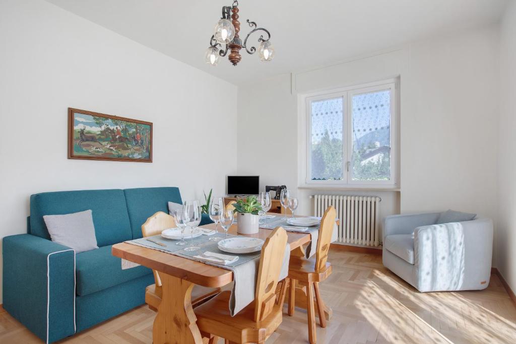 un soggiorno con un tavolo e un divano blu di La Mèison de la Louye ad Aosta