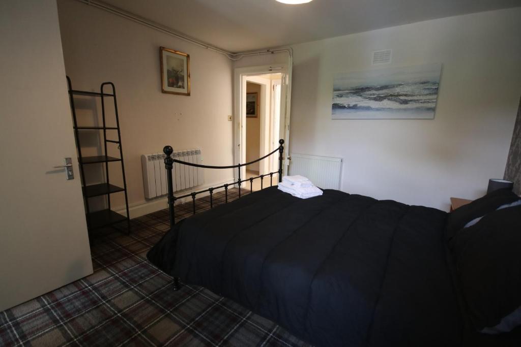 a bedroom with a black bed in a room at Stag View, River Black Water Holiday Flats, INCHBAE, GARVE, IV232PG in Garve