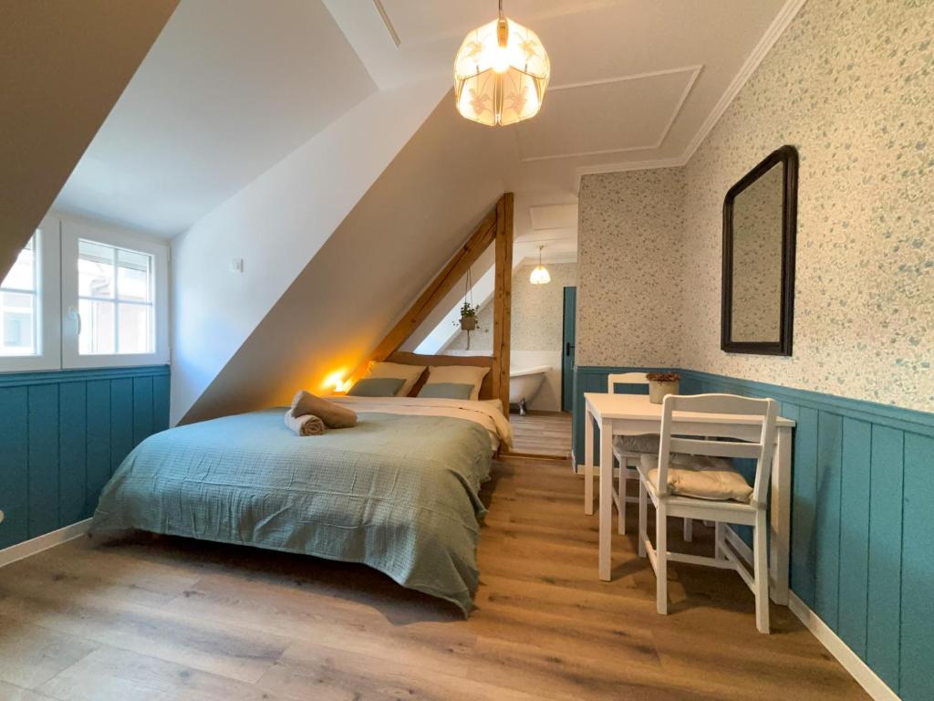 a attic bedroom with a bed and a table at English cottage - Logement atypique in Sarreguemines
