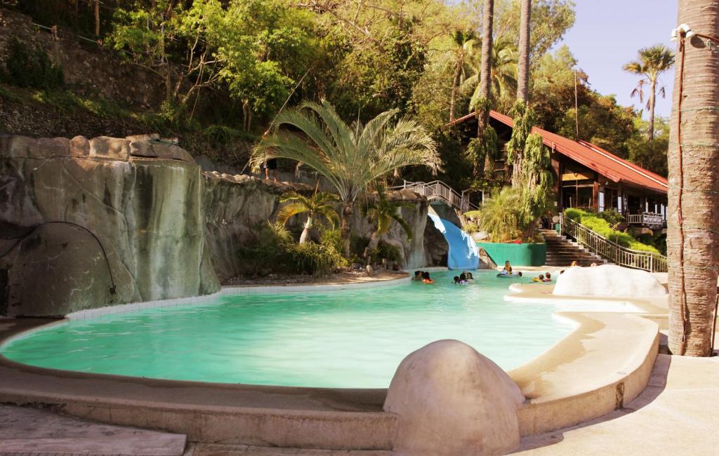 a pool at a resort with a waterfall and people in it at Eagle Point Beach and Dive Resort in Mabini
