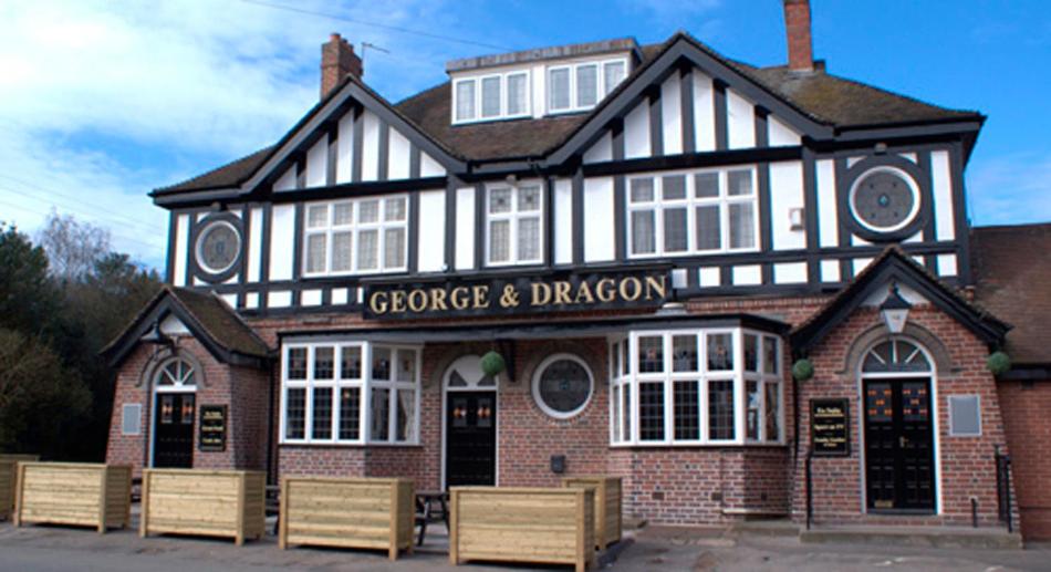 un edificio blanco y negro con bancos delante en George & Dragon, en Coleshill
