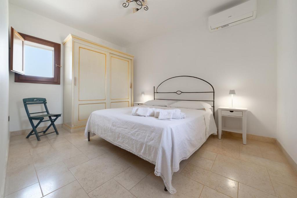 a white bedroom with a bed and a chair at Dimora Il Granaio in Masseria Galatea Agriturismo in Alessano