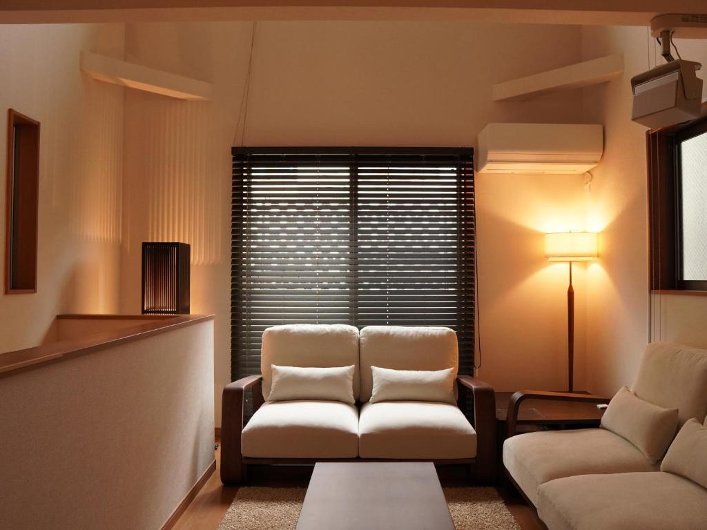 ein Wohnzimmer mit zwei Stühlen und einer Couch in der Unterkunft GOHO STAY me Sumiyoshi in Tokio