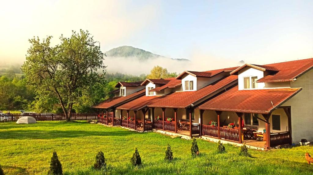 a row of houses in a field with mountains in the background at INTRE CASCADE in Baia de Arieş