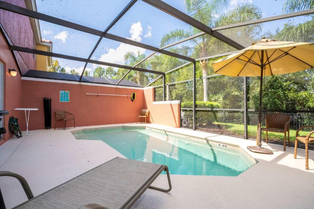 an indoor swimming pool with an umbrella and a table at Spectacular House with 3BR - Private Pool, BBQ - Minutes from Disney! in Kissimmee