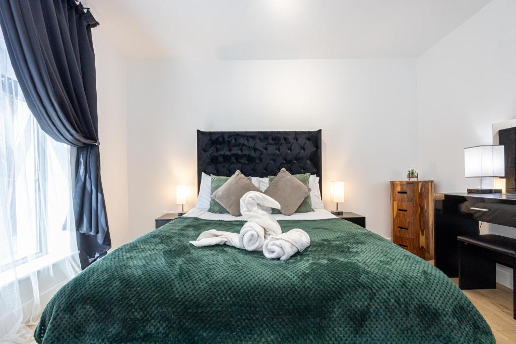 a bedroom with a green bed with towels on it at Stylish 2-Bed Apartment in Manchester City Centre in Manchester