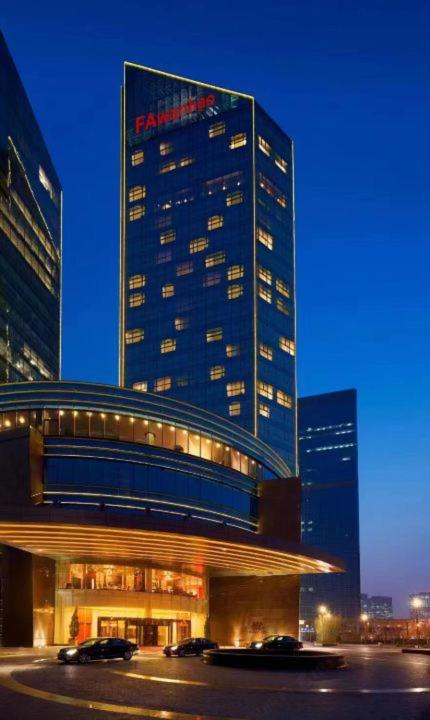 Hotel Fa万濠国际服务公寓 广州琶洲会展中心店, a tall building with cars parked in front of it at Fa万濠国际服务公寓 广州琶洲会展中心店 in Guangzhou