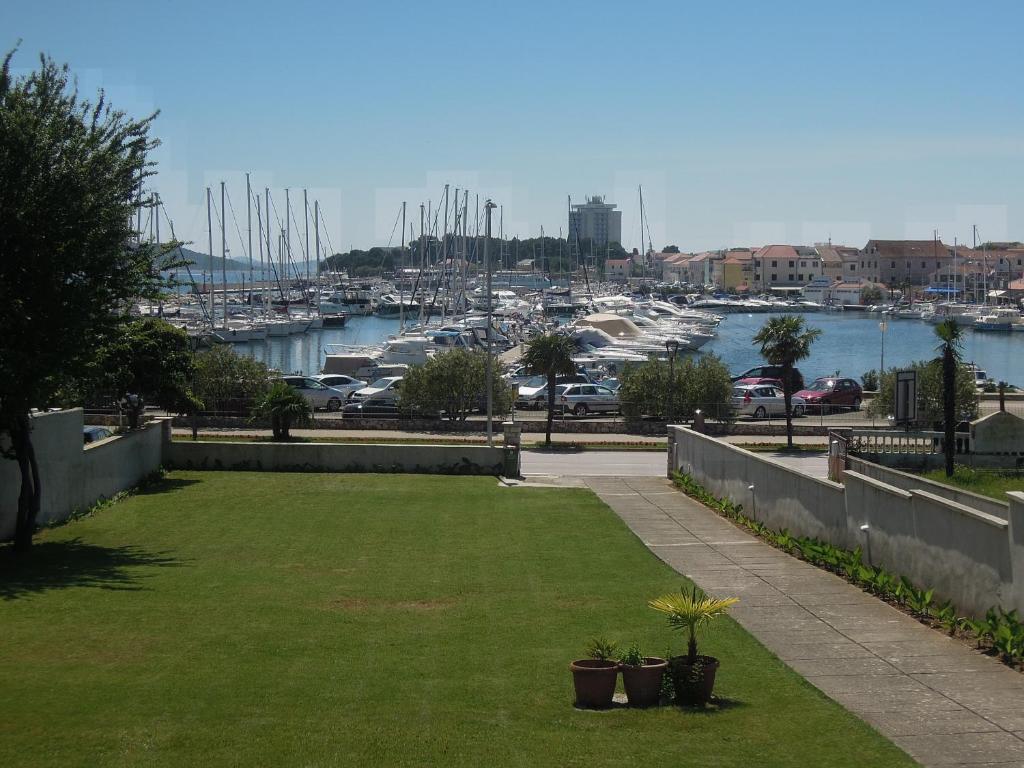 a garden with a view of a marina with boats at Apartment and Rooms Villa Kolonada in Vodice
