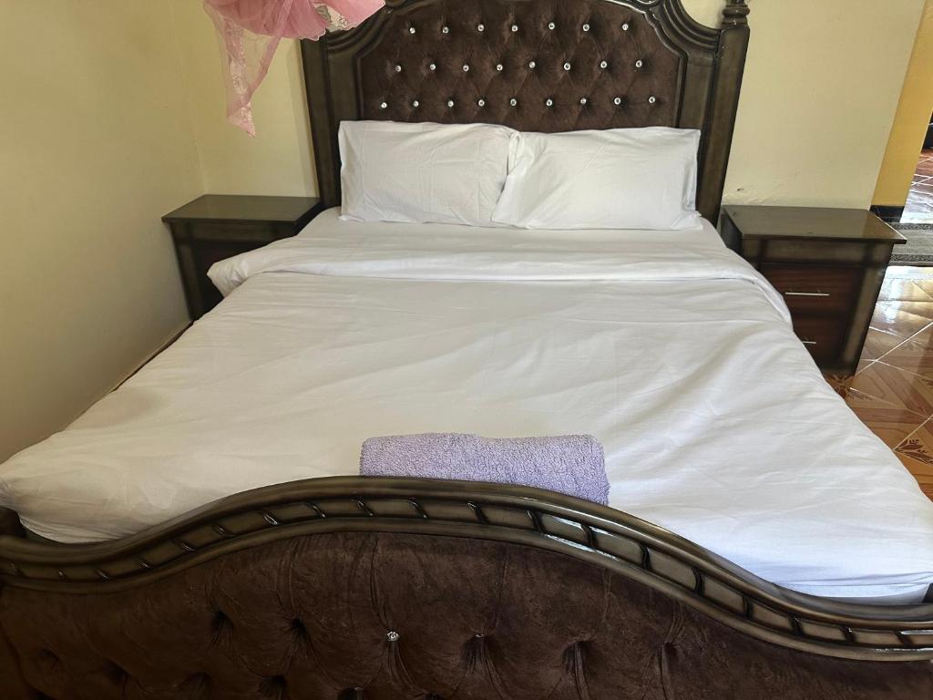 un lit avec des draps blancs et une couverture violette dessus dans l'établissement Thalia Appartement, à Nairobi