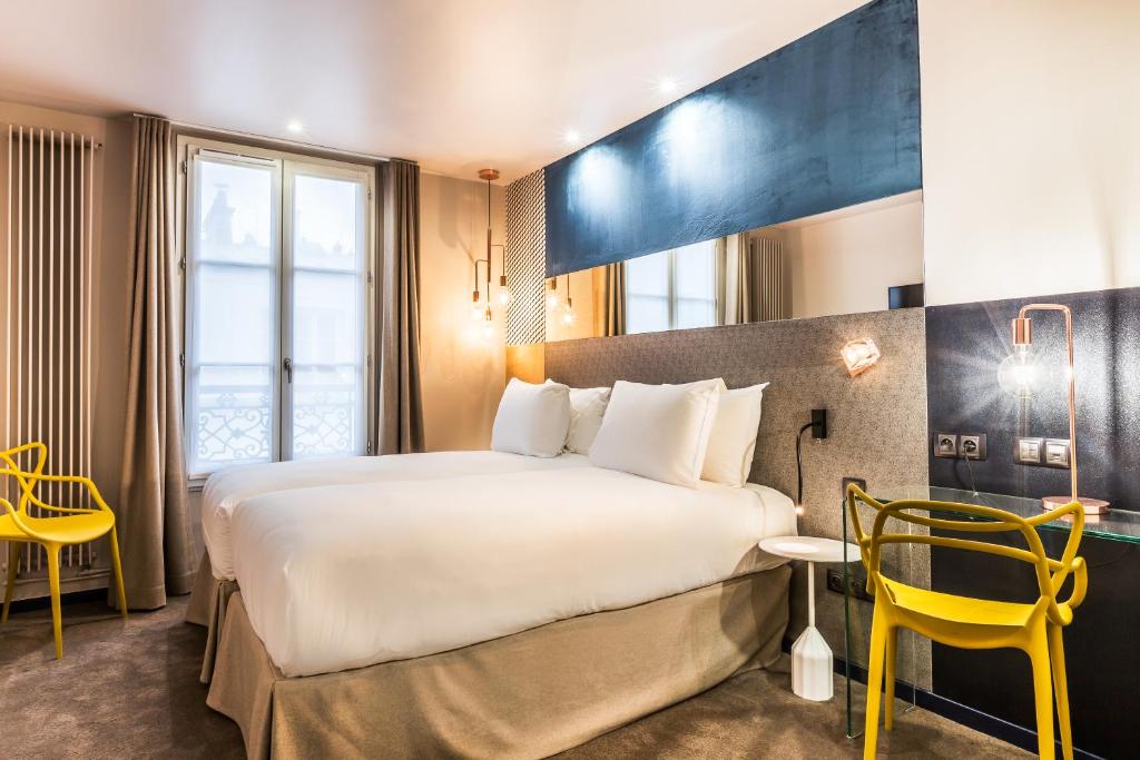 a hotel room with a large bed and a yellow chair at Hotel Duette Paris in Paris