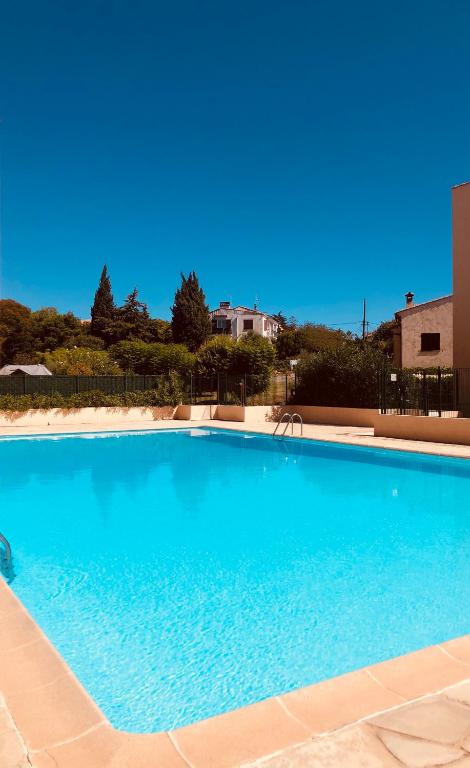 une grande piscine bleue devant un immeuble dans l'établissement Lumineux avec piscine, Wifi & Terrace - Proche plage & Aéroport, à Saint-Laurent-du-Var