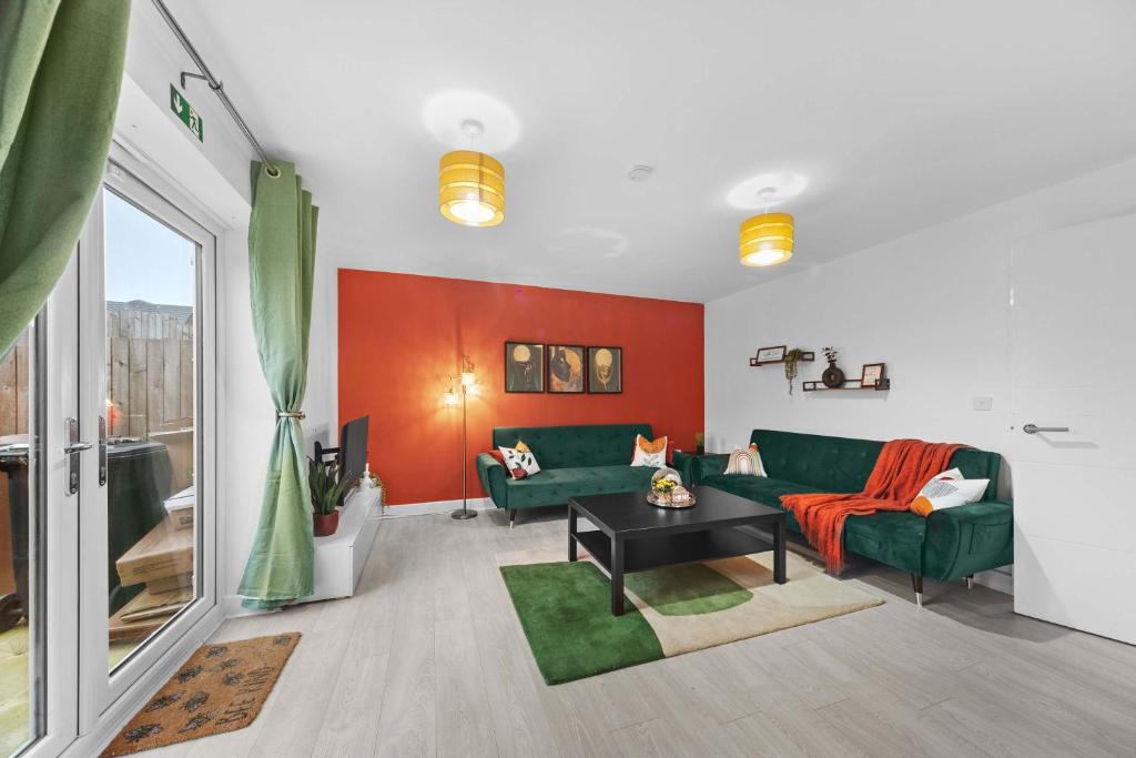 un salon avec un canapé vert et un mur rouge dans l'établissement Contractor & Family Friendly 4-BR House - Leads, à Cross Gates