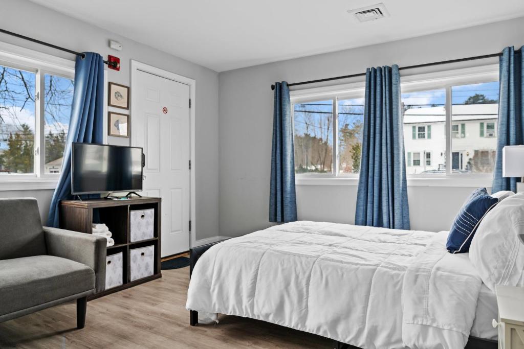 a bedroom with a bed and a chair and windows at Washington Park Motel Deluxe Suite in Norwell
