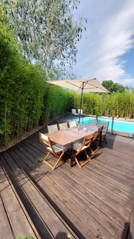 a wooden deck with a table and chairs and an umbrella at Bienvenue chez PO et Marie in Montferrier-sur-Lez