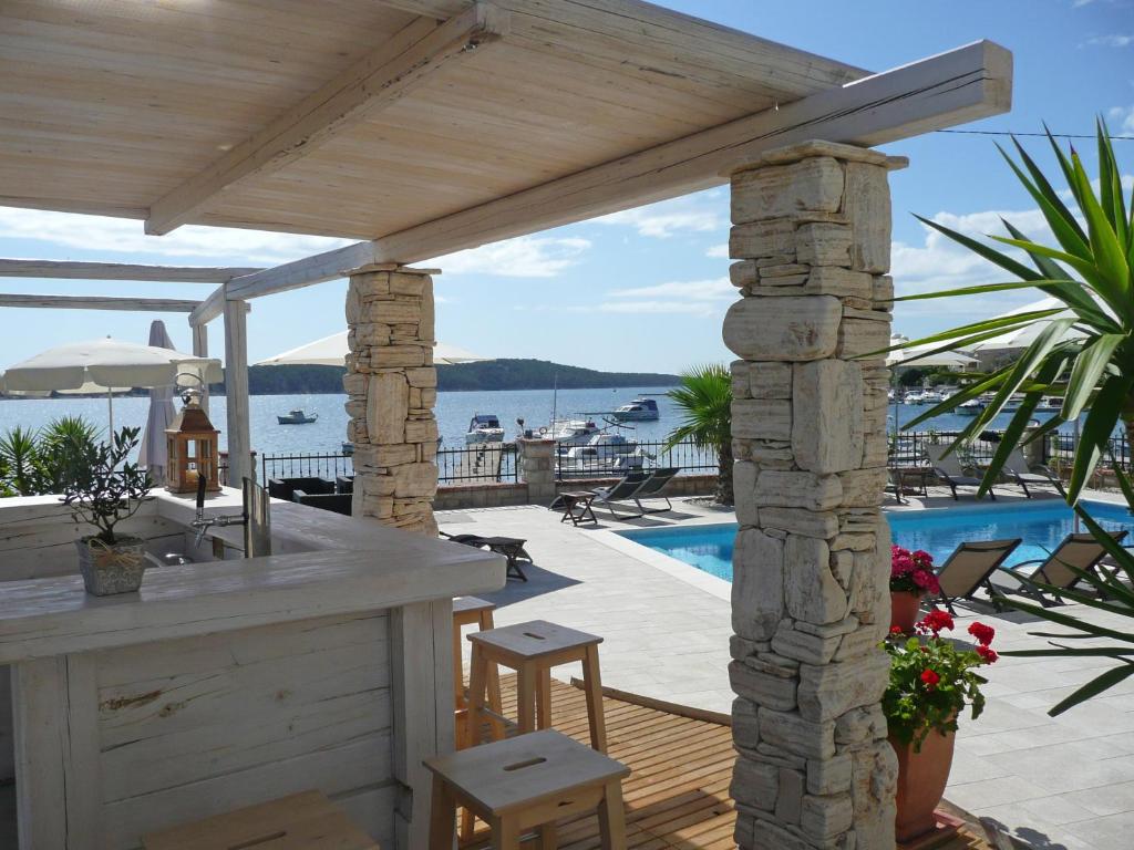 a patio with a bar and a swimming pool at Guest House Villa Papalina in Rab